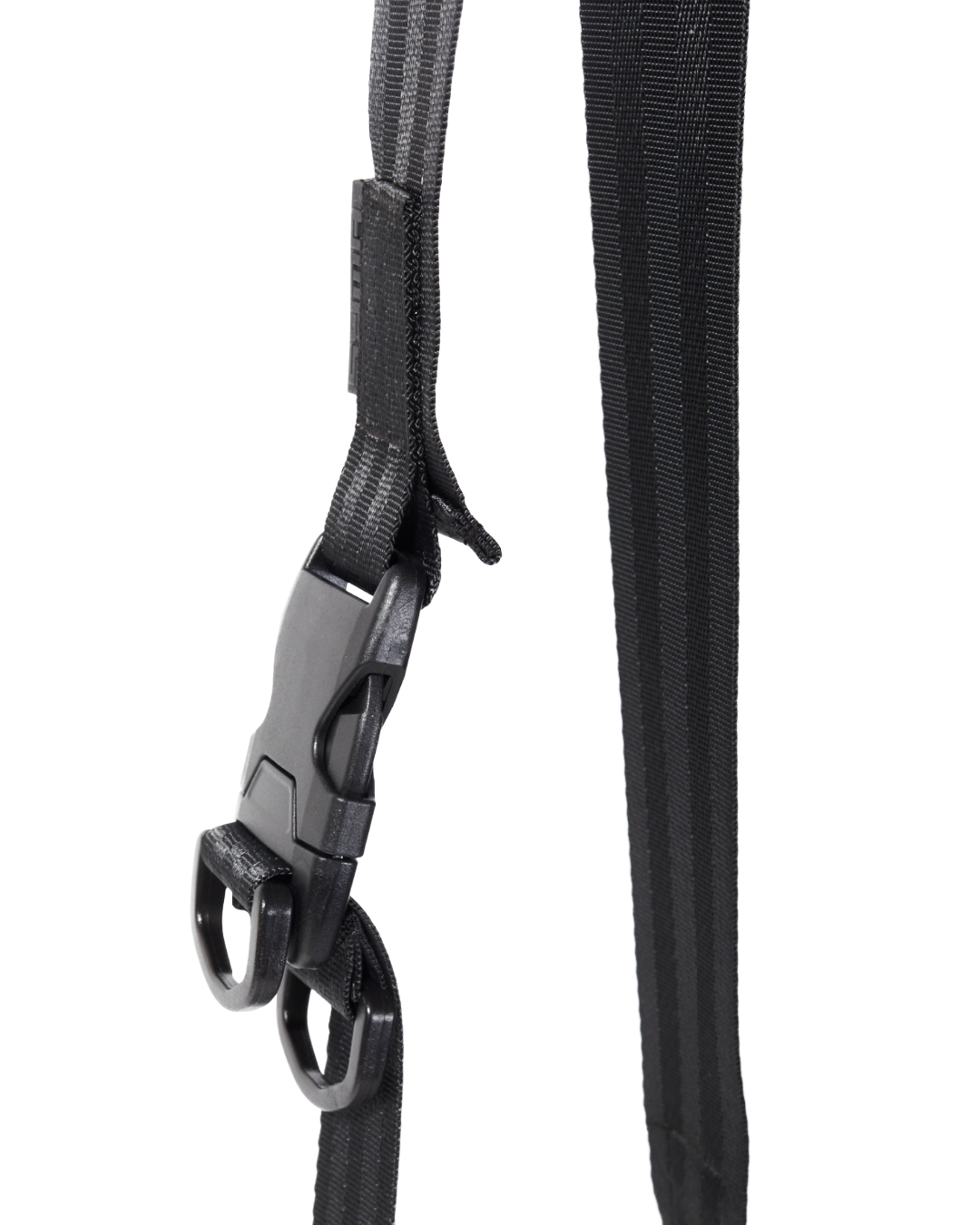 Close-up view of the black SYMA Sense Sling Bag strap highlighting its heavy-duty quick-release buckle, D-rings, and ribbed nylon webbing. Minimalist drawstring sling bag.