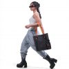 Full-body profile of a female model in modern streetwear carrying the black SYMA Noble minimalist everyday tote bag featuring contrasting orange paracord straps