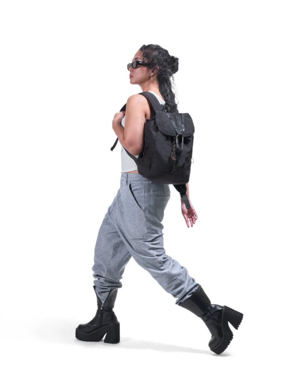 Woman in edgy urban streetwear carrying black SYMA Adore Backpack on shoulder. 11L compact everyday backpack