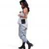 Female model in urban streetwear showcasing the black SYMA Arrival compact travel wallet worn as a hanging neck pouch bag over a white silk top and denim jeans