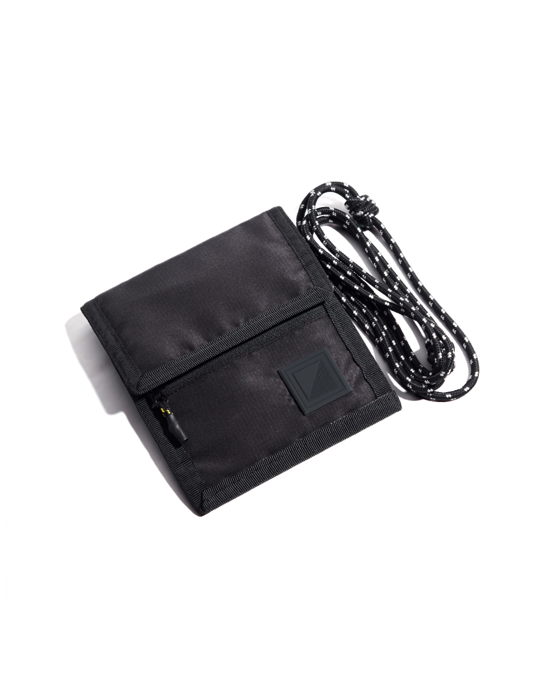 Front exterior view of the closed black SYMA Arrival compact travel wallet, highlighting the ripstop fabric, zippered front pocket for small essentials, and attached paracord strap