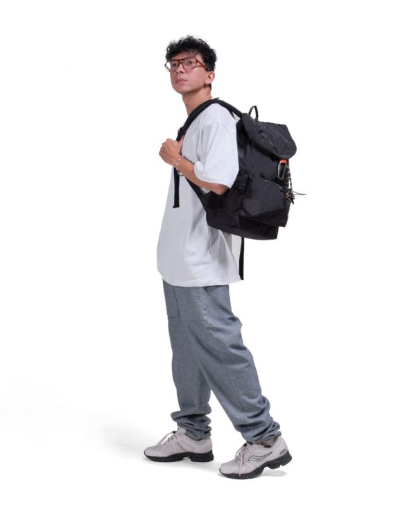Man in casual streetwear wearing black SYMA Outrun Backpack. 21L versatile everyday backpack