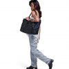 Woman in urban smart-casual attire carrying black SYMA Miles Tote Bag on shoulder. 16L versatile work tote bag
