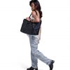 Woman in urban smart-casual attire carrying black SYMA Miles Tote Bag on shoulder. 16L versatile work tote bag