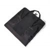 Angled view of the folded black SYMA Motion laid flat, highlighting its durable hexagon ripstop texture, sleek exterior, and top handles. Travel garment bag.