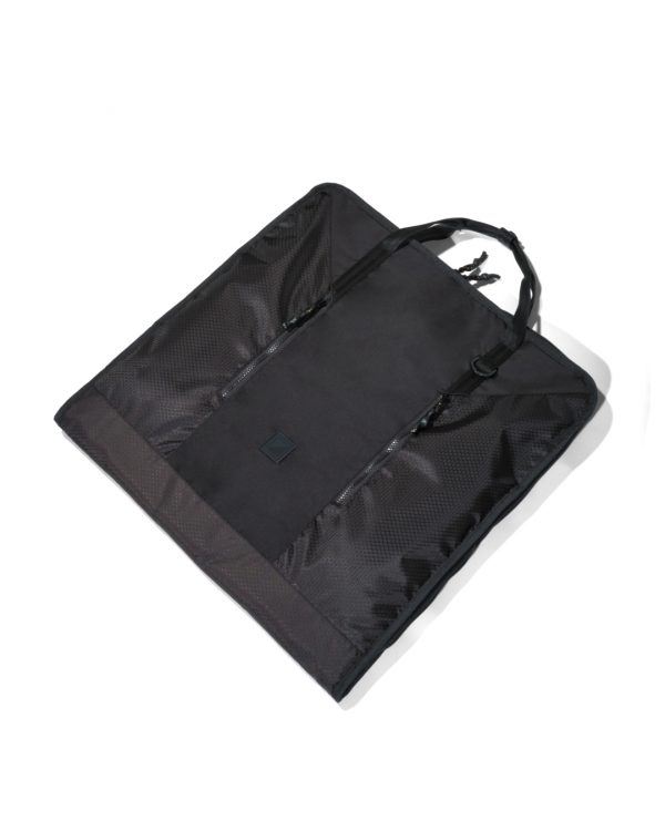Angled view of the folded black SYMA Motion laid flat, highlighting its durable hexagon ripstop texture, sleek exterior, and top handles. Travel garment bag.