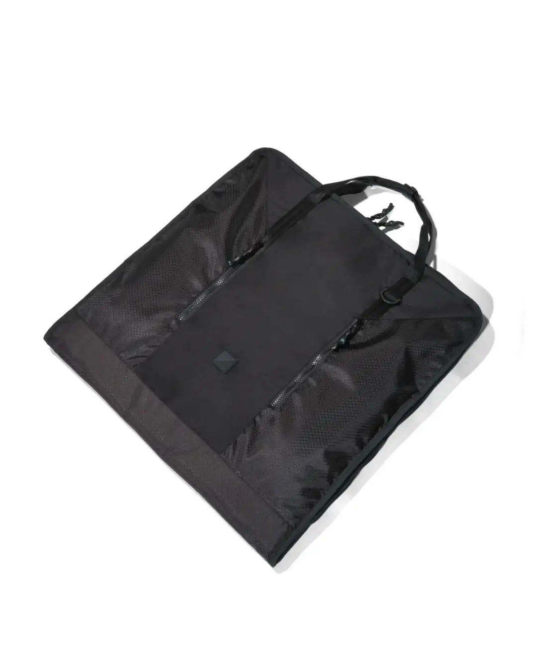 Angled view of the folded black SYMA Motion laid flat, highlighting its durable hexagon ripstop texture, sleek exterior, and top handles. Travel garment bag.