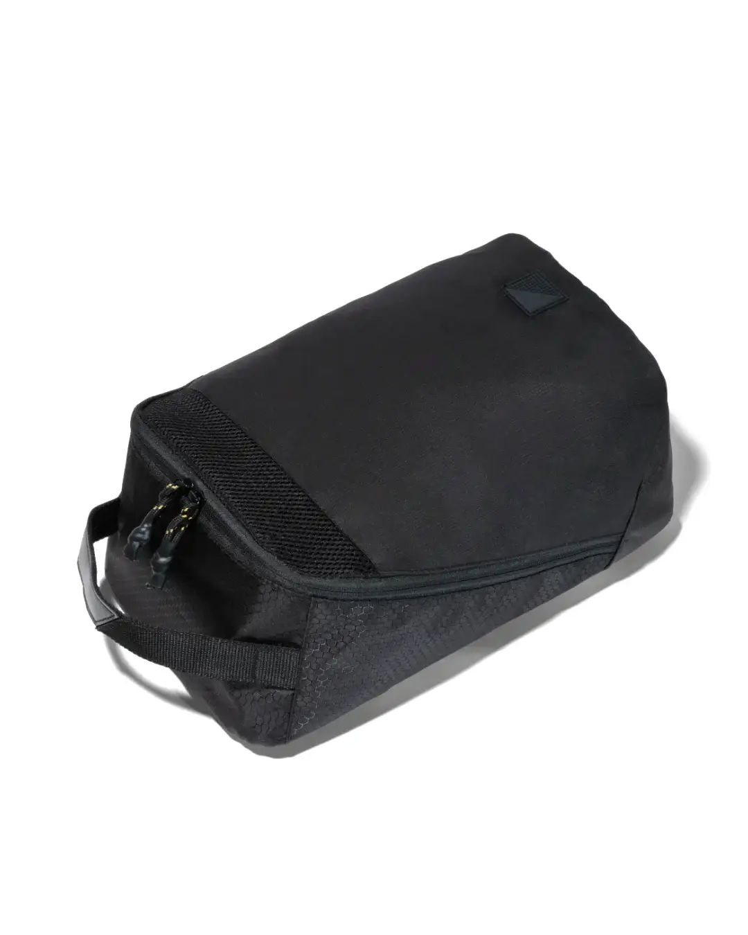 High-angle view of black SYMA Cubic laid flat, highlighting its streamlined profile, top grab handle, and upper mesh ventilation panel. Ventilated travel shoe bag.