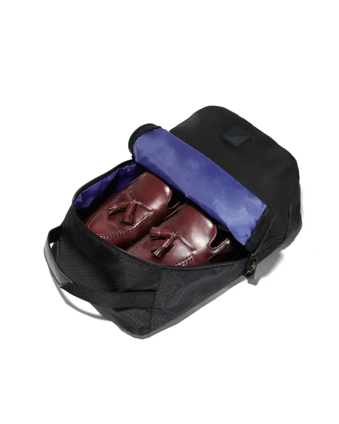 High-angle view of an open black SYMA Cubic showing a pair of brown leather loafers inside its bright blue interior. Ventilated travel shoe bag.