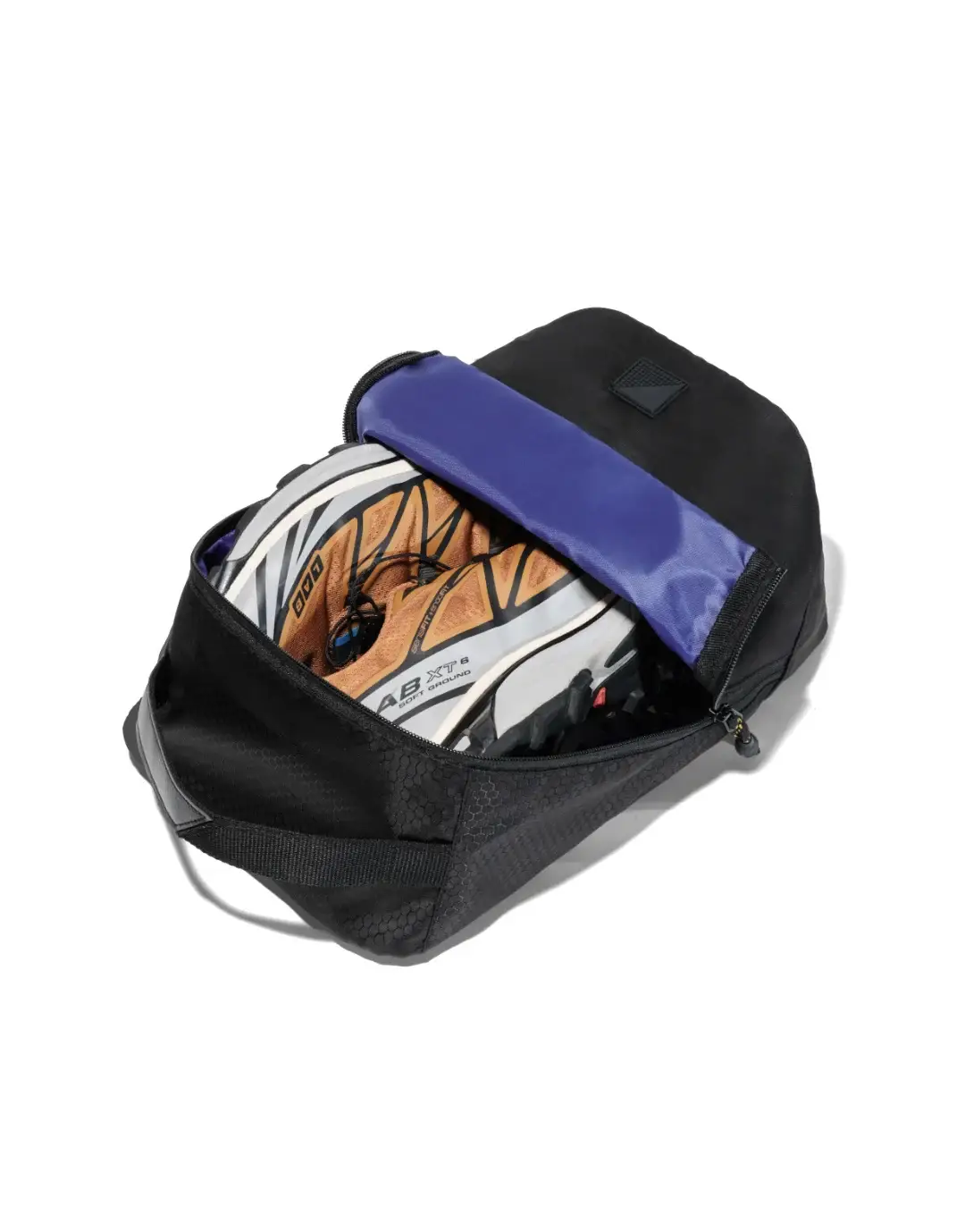 High-angle view of an open black SYMA Cubic showing a pair of trail running sneakers inside its bright blue interior. Ventilated travel shoe bag.