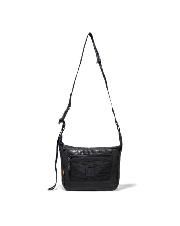 Straight suspended front view of the black SYMA Strings Sling Bag highlighting its structured PE Tarpaulin top panel, zippered front mesh pocket, and adjustable strap. Small urban crossbody bag.