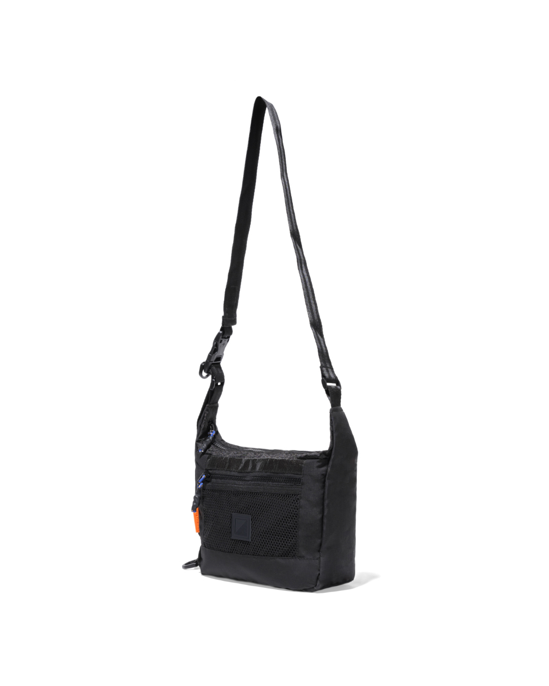 Angled suspended view of the black SYMA Strings Sling Bag highlighting its structured 9cm depth profile, glossy PE Tarpaulin top panel, and front mesh pocket. Small urban crossbody bag.