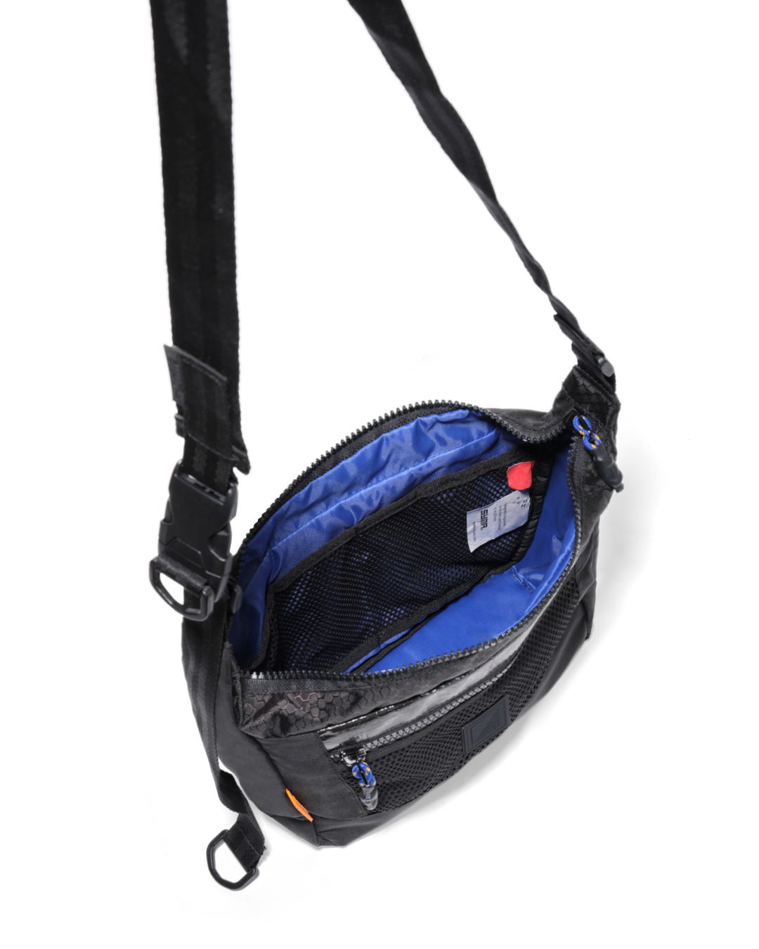 High-angle open interior view of the black SYMA Strings Sling Bag highlighting its high-contrast blue lining, internal mesh pocket, and tactical strap. Small urban crossbody bag.