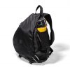 Angled side view of the black SYMA Symmetry Crossbody Bag resting on a white surface, highlighting its expandable side mesh pocket holding a yellow water bottle and hexagon ripstop exterior. Large techwear crossbody bag.
