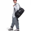 Man in athletic leisure attire walking while carrying the black SYMA Wonder Duffle Bag across his shoulder. A 38L versatile weekend duffle bag.