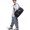 Man in athletic leisure attire walking while carrying the black SYMA Wonder Duffle Bag across his shoulder. A 38L versatile weekend duffle bag.