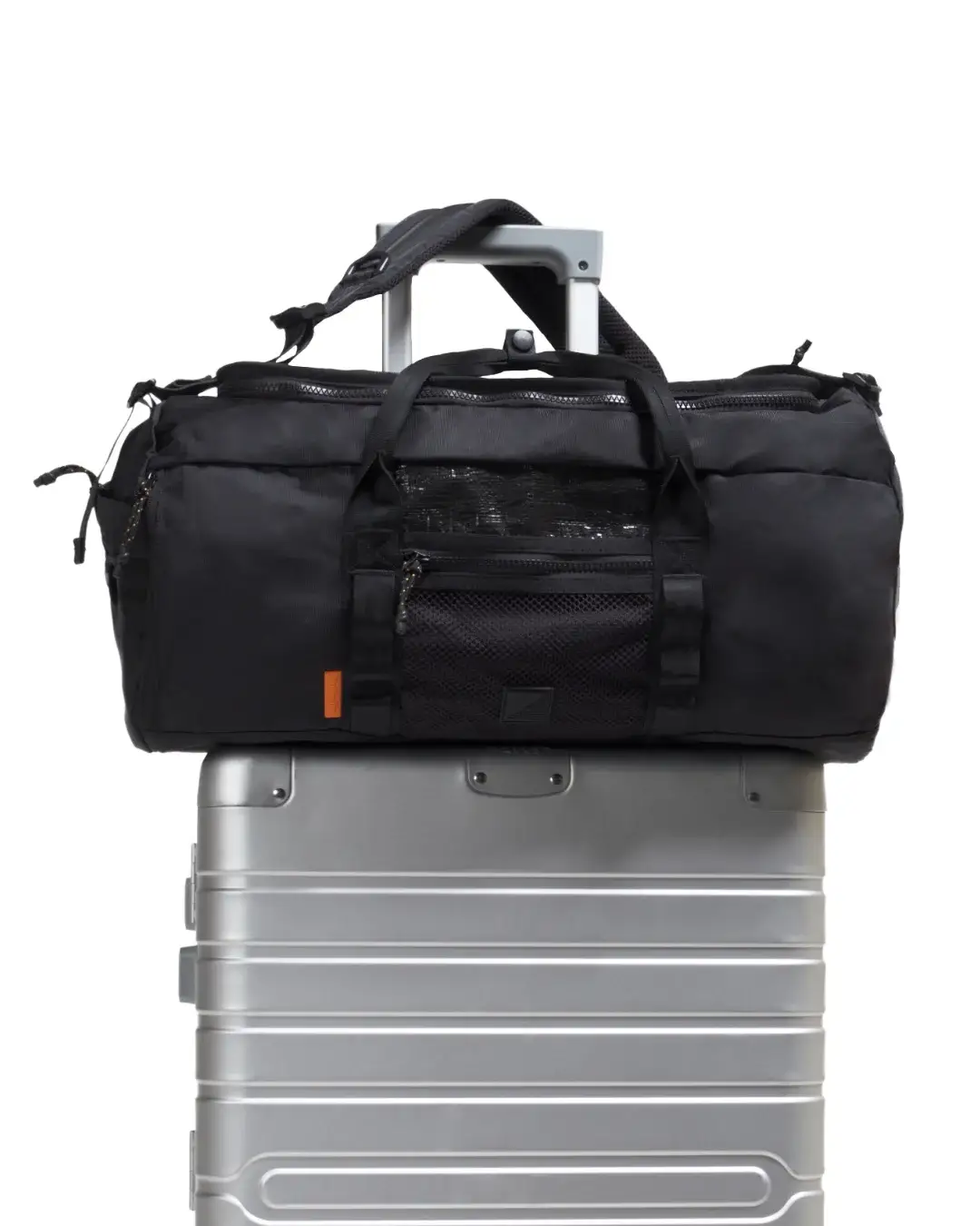 Front view of black SYMA Wonder Duffle Bag resting on top of a silver suitcase, highlighting its front mesh pocket and travel readiness. Versatile weekend duffle bag.