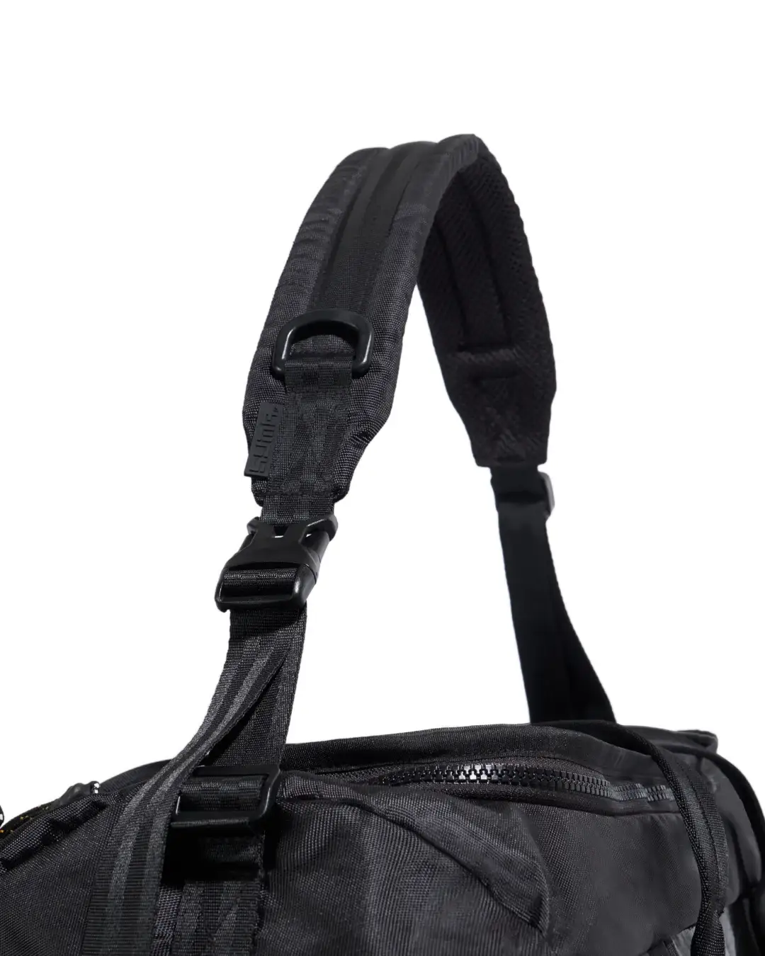 Close-up view of black SYMA Wonder Duffle Bag highlighting thick padded shoulder strap, D-ring, and adjustable buckle. Versatile weekend duffle bag.
