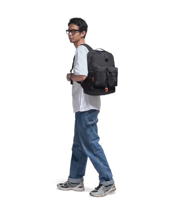 Man in casual urban attire walking with black SYMA Ascend Backpack on his back. 20L structured everyday backpack