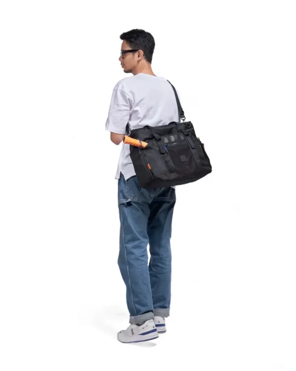 SYMA. Miles Racket-Tote Black worn by man carrying racket. Premium urban utility padel & tennis bag