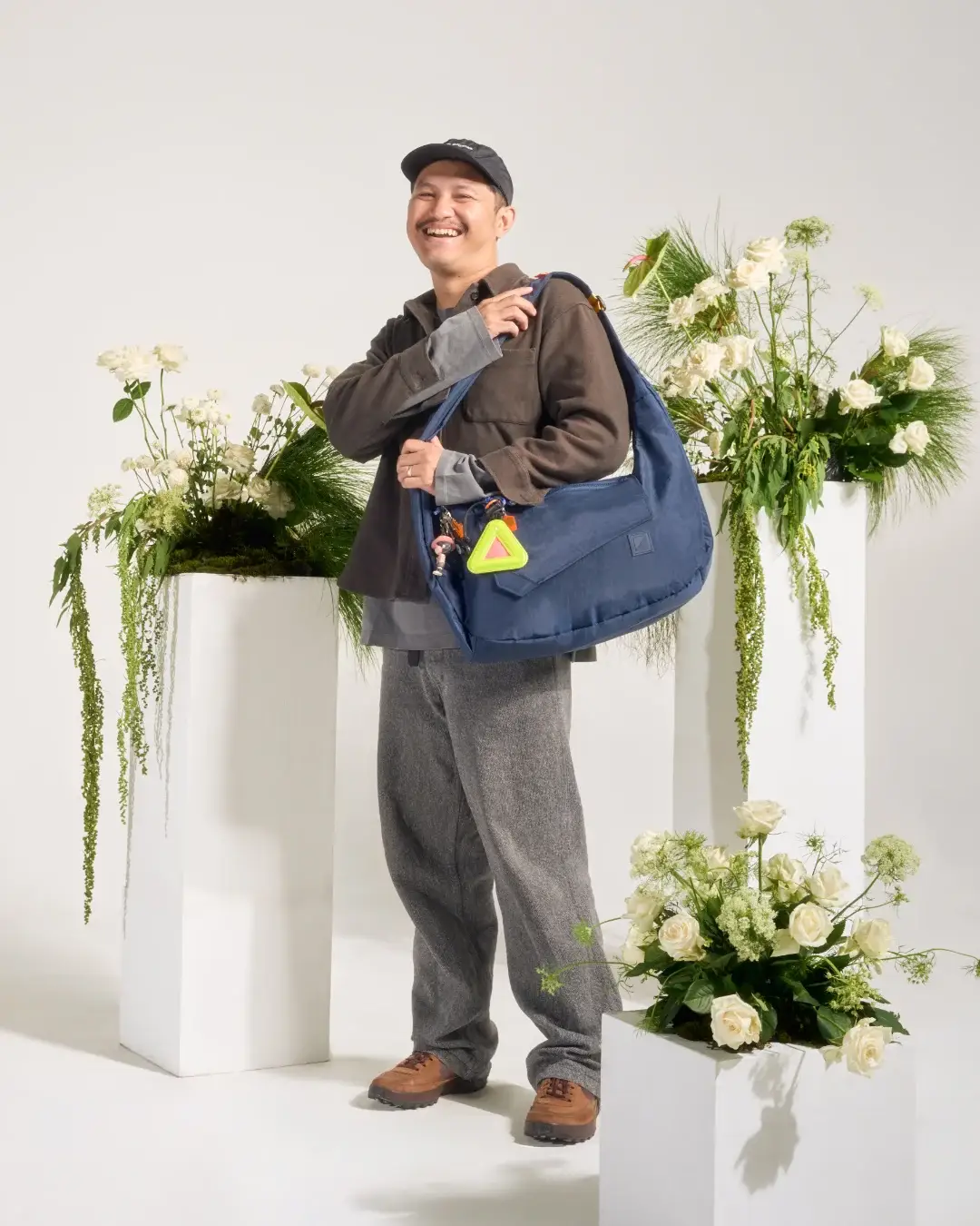 Smiling man in smart casual attire wearing SYMA Fable Sling Bag Navy on shoulder. 16L everyday commuter sling bag