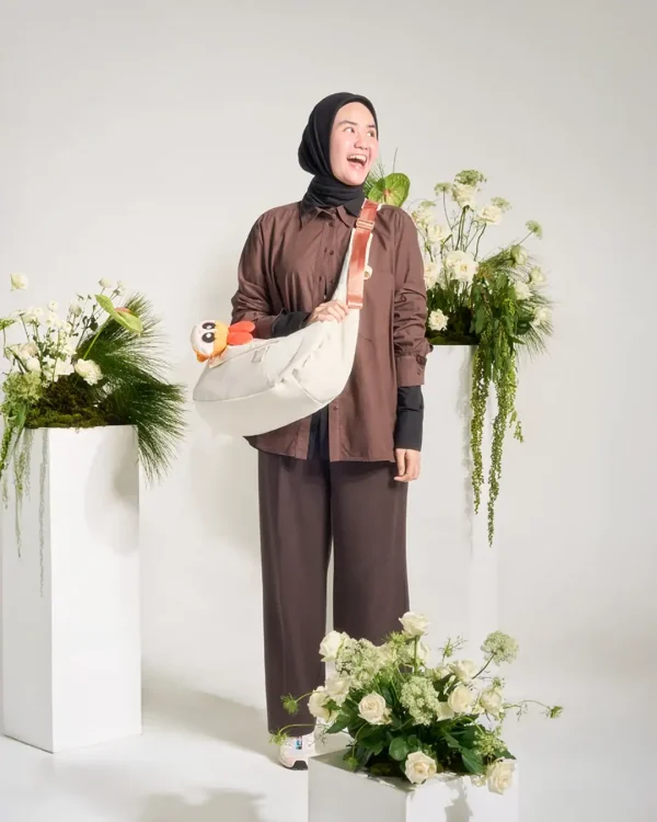 Woman wearing SYMA Fable Sling Bag Light Cream on shoulder. 16L minimalist everyday sling bag
