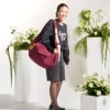 Smiling woman wearing SYMA Fable Sling Bag Maroon with oversized top. 16L urban streetwear sling bag