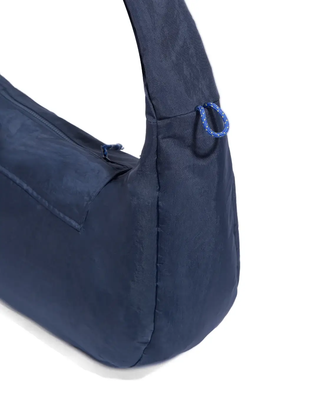 Close-up view of SYMA Fable Sling Bag Navy highlighting side charm loop and zipper details. Everyday commuter sling bag