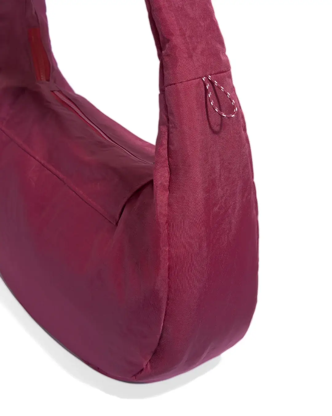 Close-up view of SYMA Fable Sling Bag Maroon highlighting side charm loop and zipper details. Urban streetwear sling bag